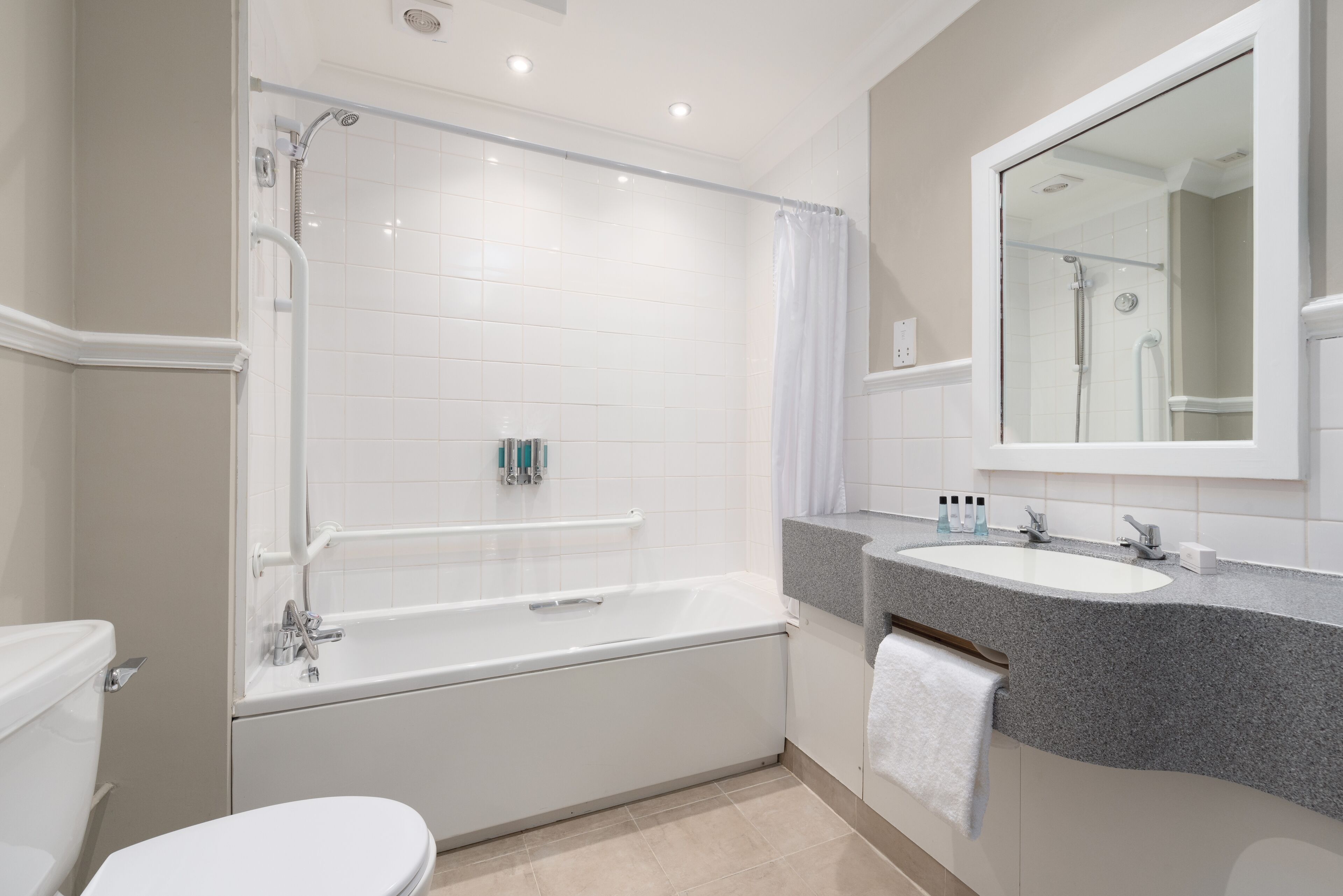 A modern bathroom with a bathtub, a toilet, a sink, and a mirror.