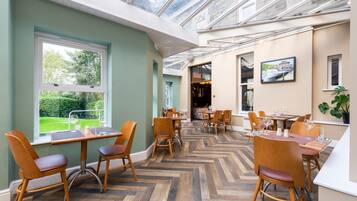 A restaurant with wooden chairs and tables, a herringbone floor, and a view through a glass ceiling.
