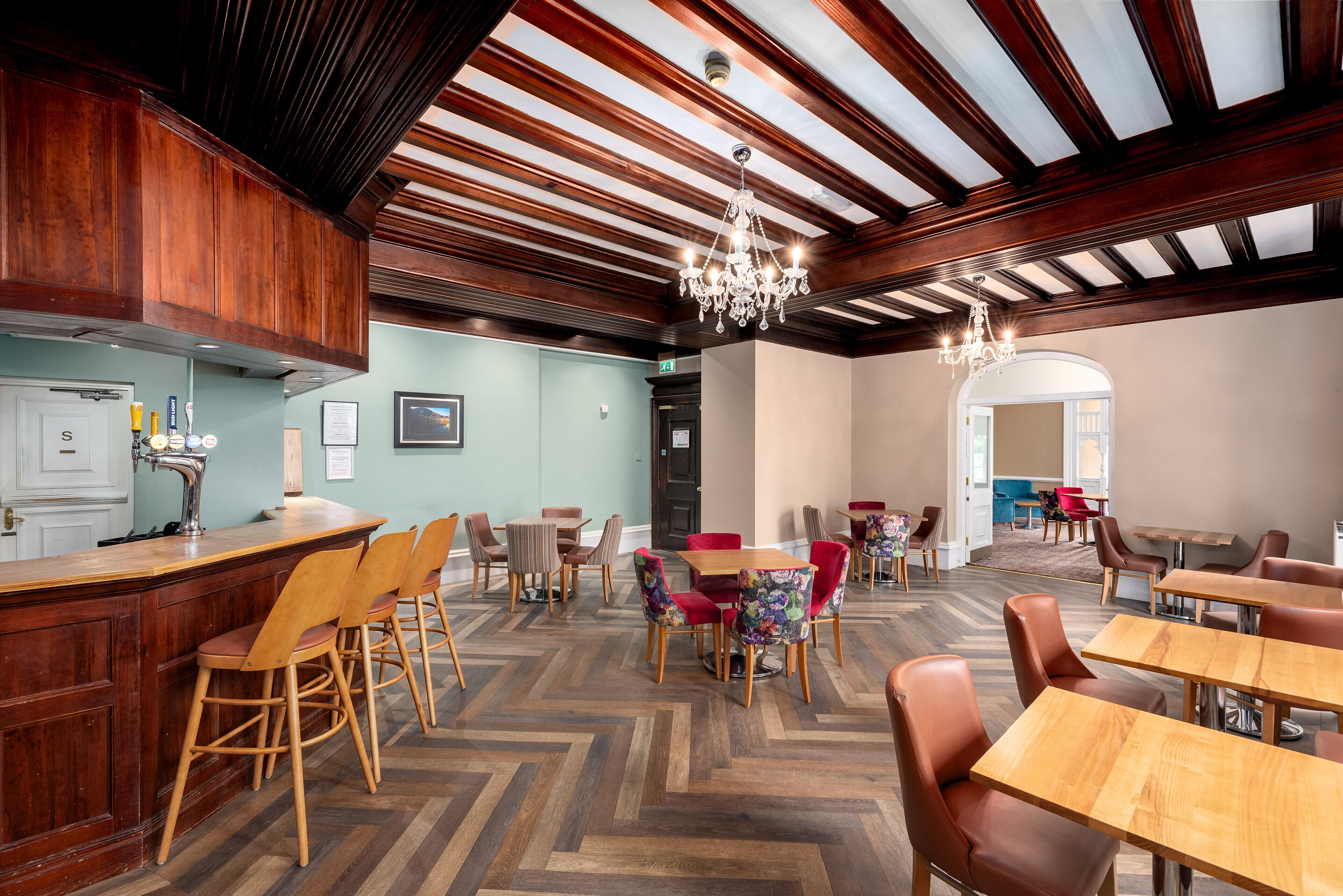 A restaurant with wooden bar and herringbone-patterned flooring.