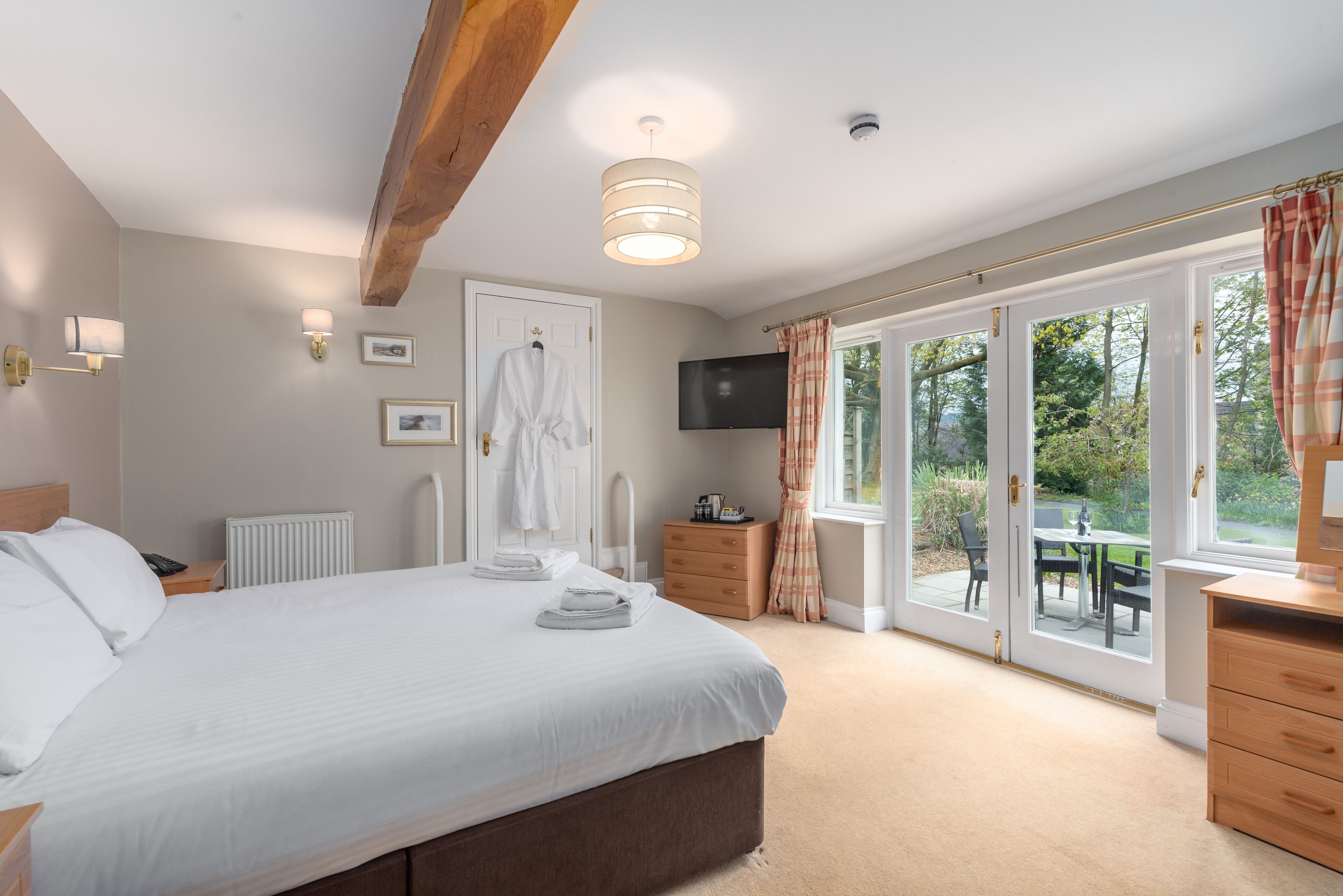 A bedroom with a large bed, a TV, a radiator, and a sliding glass door to a patio.