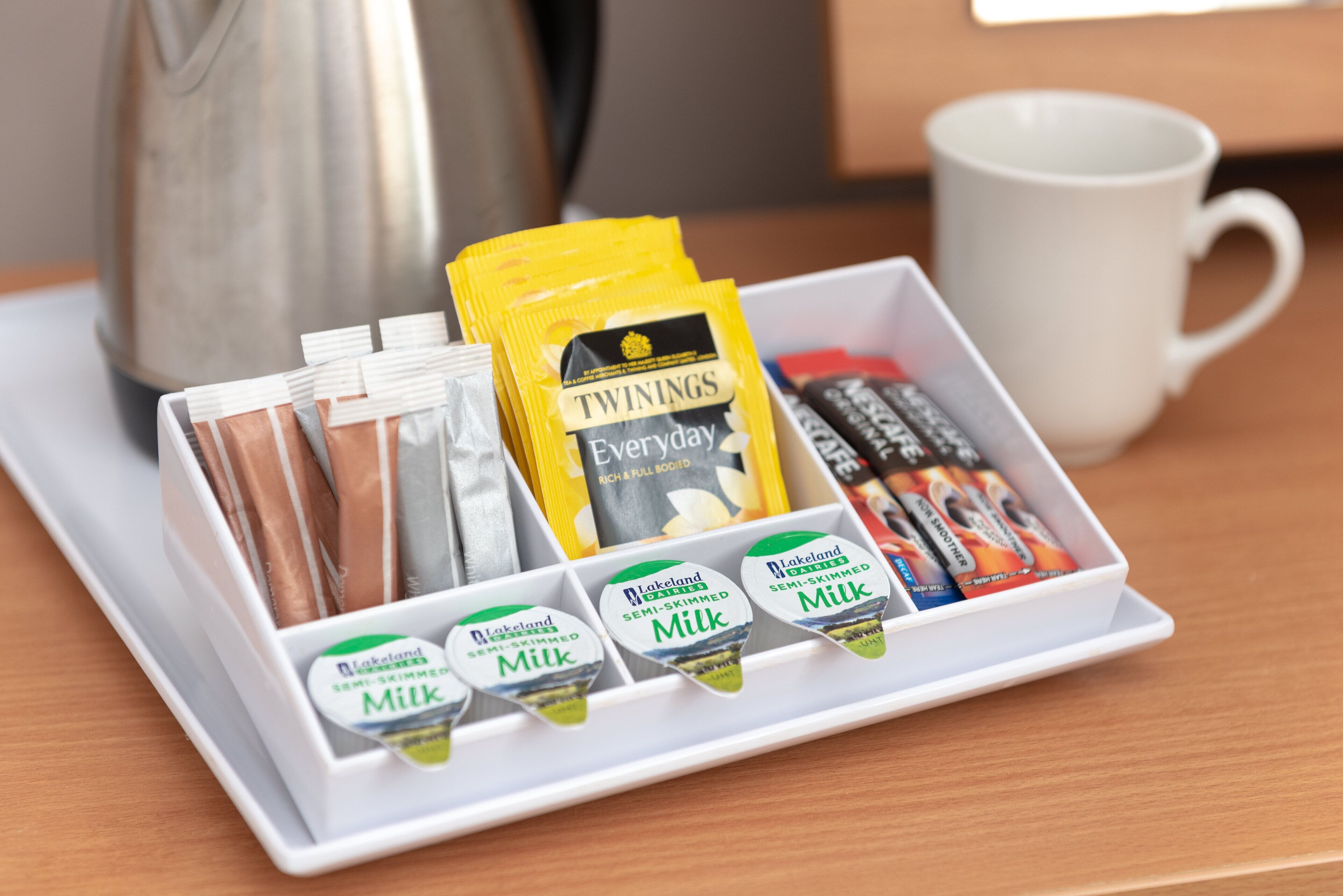 Ein Tablett mit verschiedenen Speisen, darunter Twinings Tee, Milch und Schokoladentafeln.