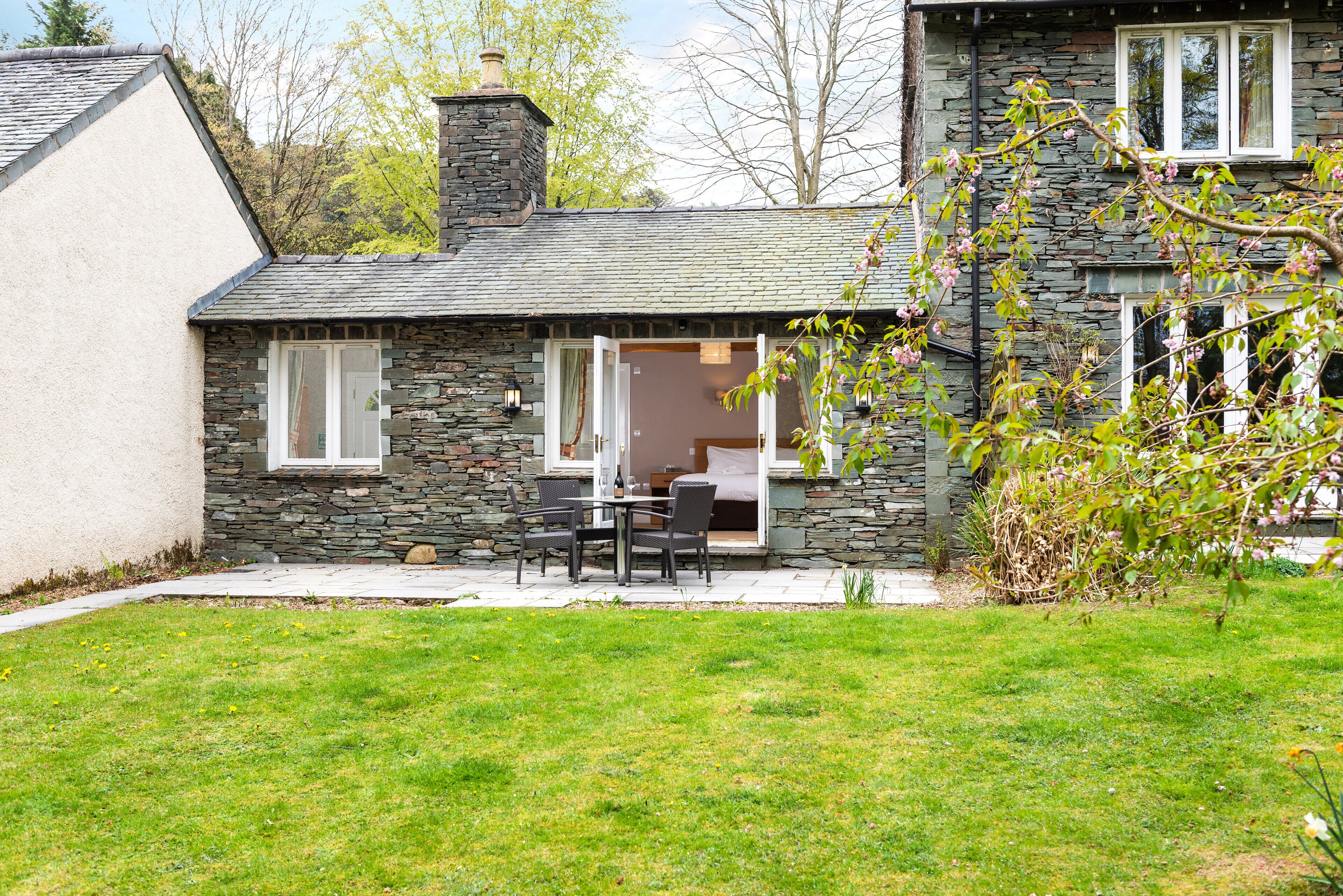 A stone house with a patio, a dining area, and a view of the surrounding landscape.