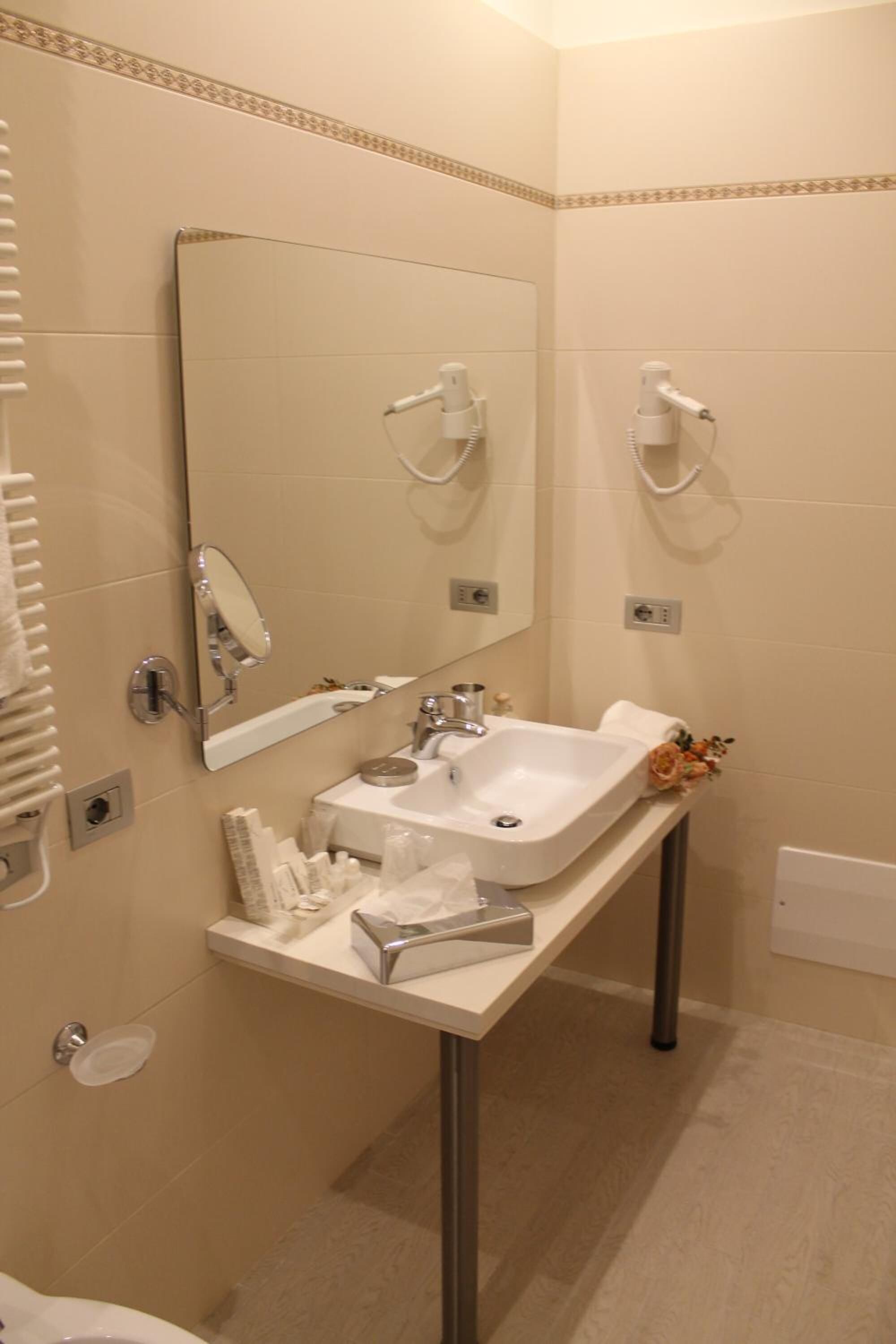 Un bany amb un lavabo, mirall, penjador de tovalloles i un objecte decoratiu petit.