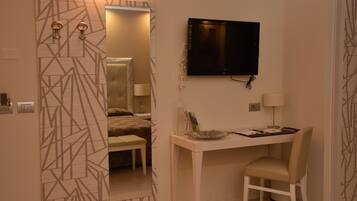 Ein modernes Schlafzimmer mit Bett, Schreibtisch und Fernseher.