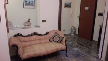 Ein Zimmer mit einer Couch im Vintage-Stil, einem dekorativen Spiegel und einem gemusterten Teppich.