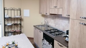 A compact kitchen with a gas stove, a sink, and wooden cabinets. - B&B Agave (Reggio Calabria)