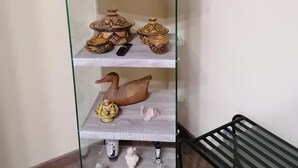 A glass display shelf with various decorative items including pottery, a wooden duck, and small figurines. - B&B Agave (Reggio Calabria)