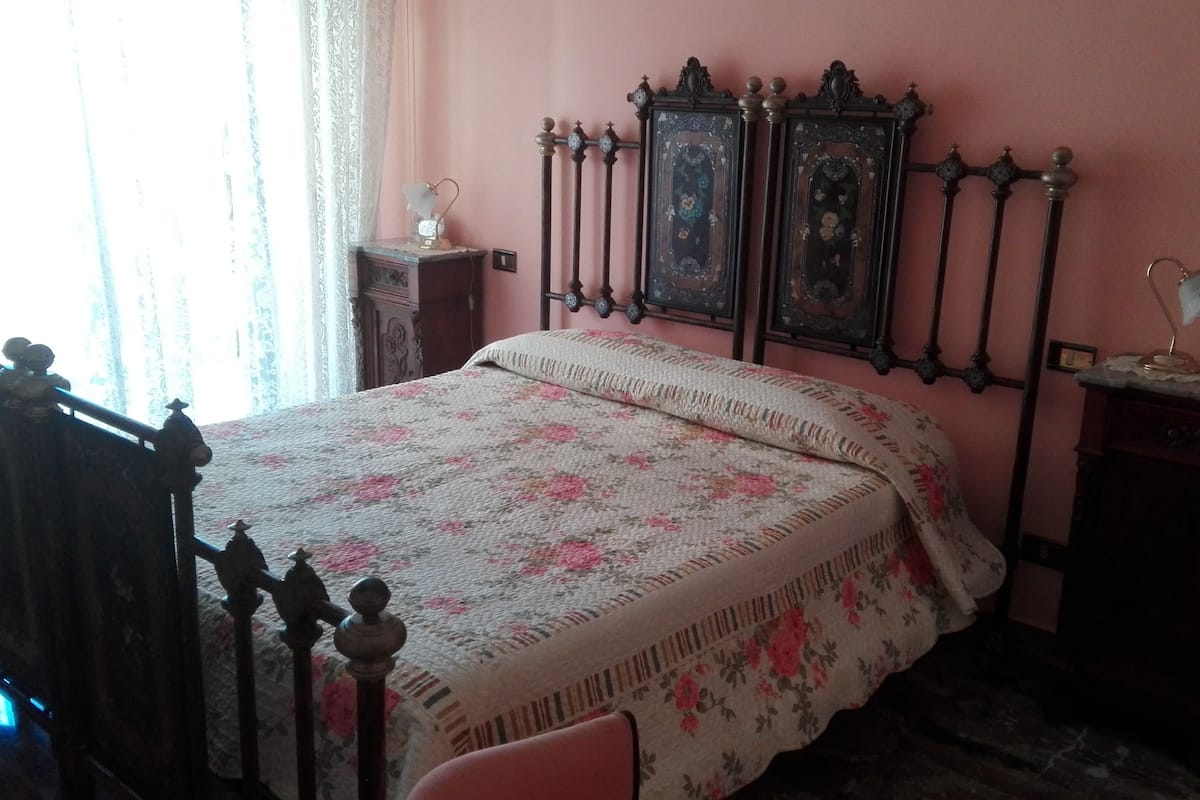 A bedroom with a bed, a nightstand, a dresser, and a window with curtains.