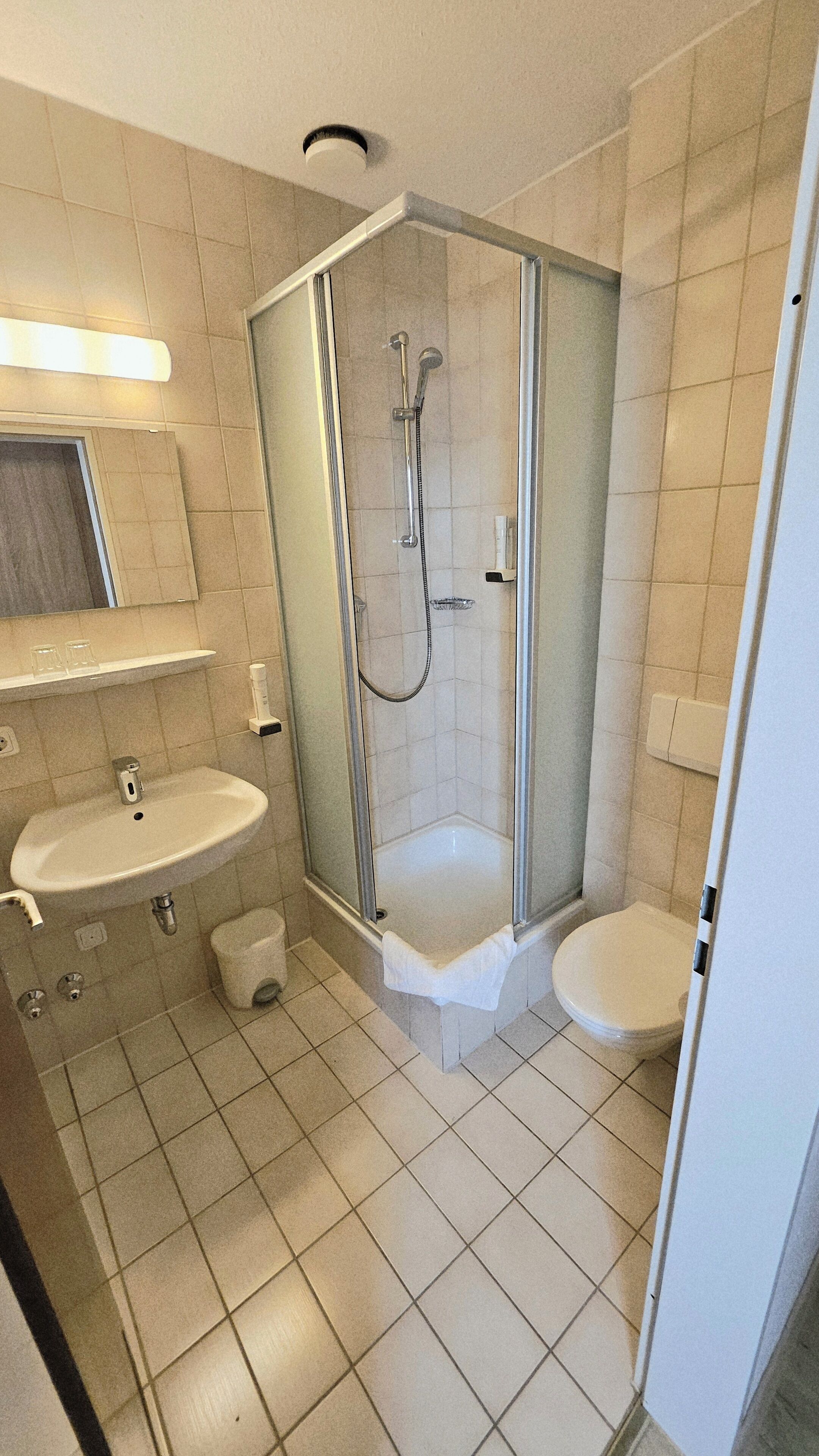 Moderni kylpyhuone, jossa on lasiseinällä varustettu suihku, pesuallas ja wc.