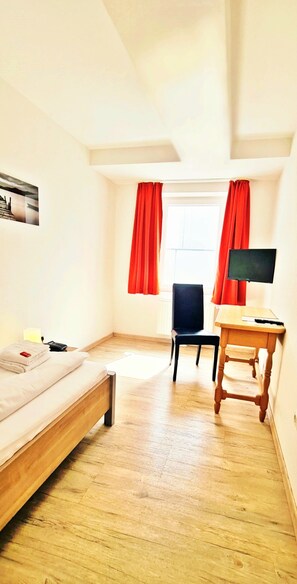 A bedroom with a bed, a desk, a chair, and a TV. - Hotel Krone (Koenigsbrunn)