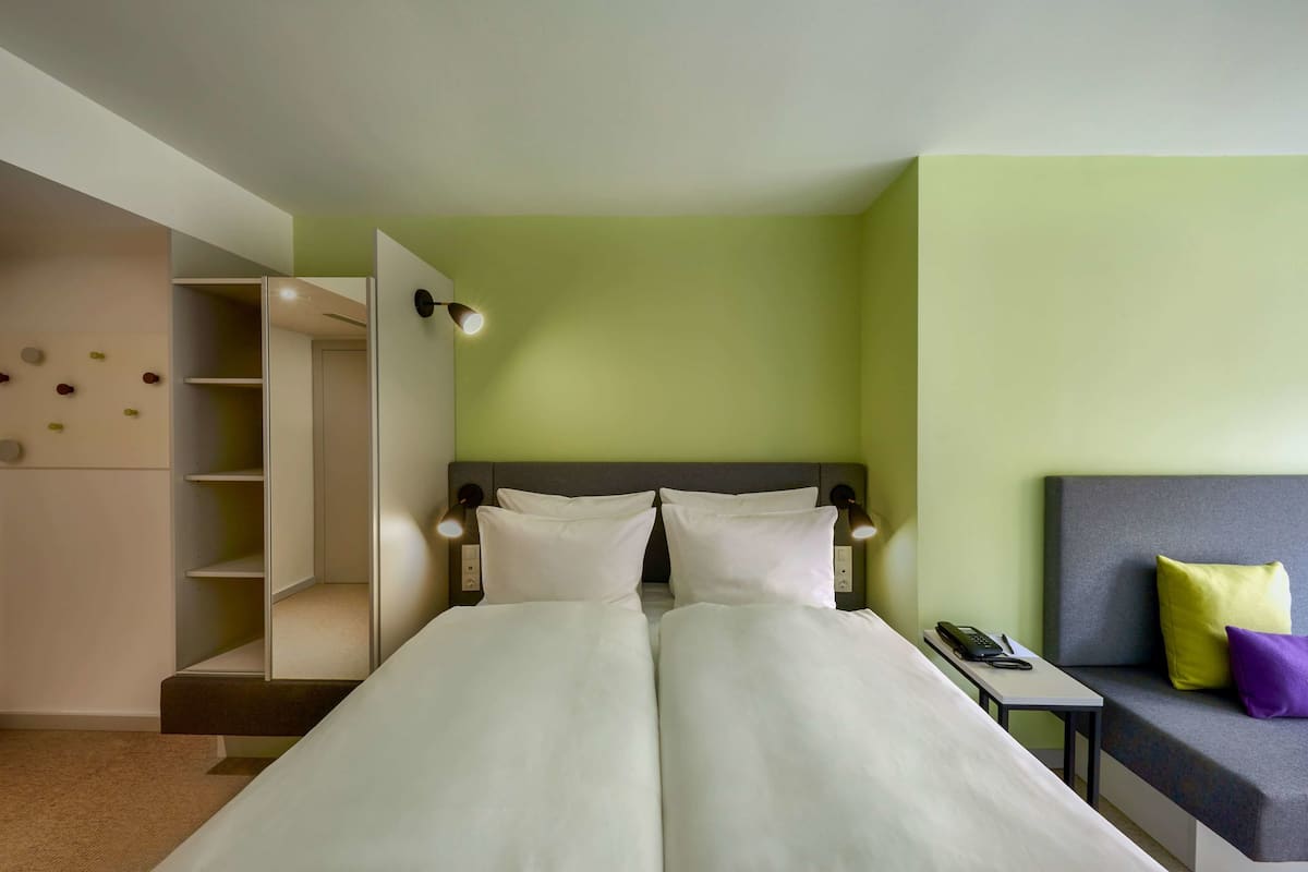 Ein Hotelzimmer mit einem Bett, einem Nachttisch und einer Couch mit Kissen.
