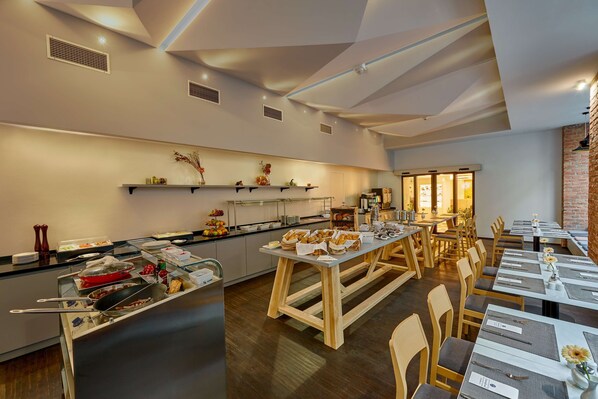 Un espace repas moderne avec de longues tables, un buffet et un mur décoratif en briques.