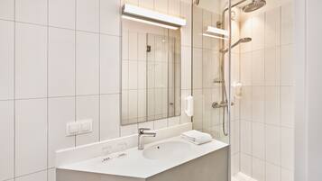 Un bagno moderno con uno specchio grande, un lavandino e una doccia.