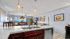 A modern kitchen with a large island, stainless steel appliances, and pendant lighting. - Hale Kamaole 208 - Relax and Enjoy Your Beautiful Ocean View Suite (Kihei)