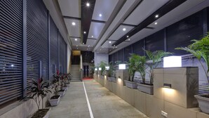 Un pasillo moderno con plantas en macetas, iluminación empotrada y piso de baldosas.