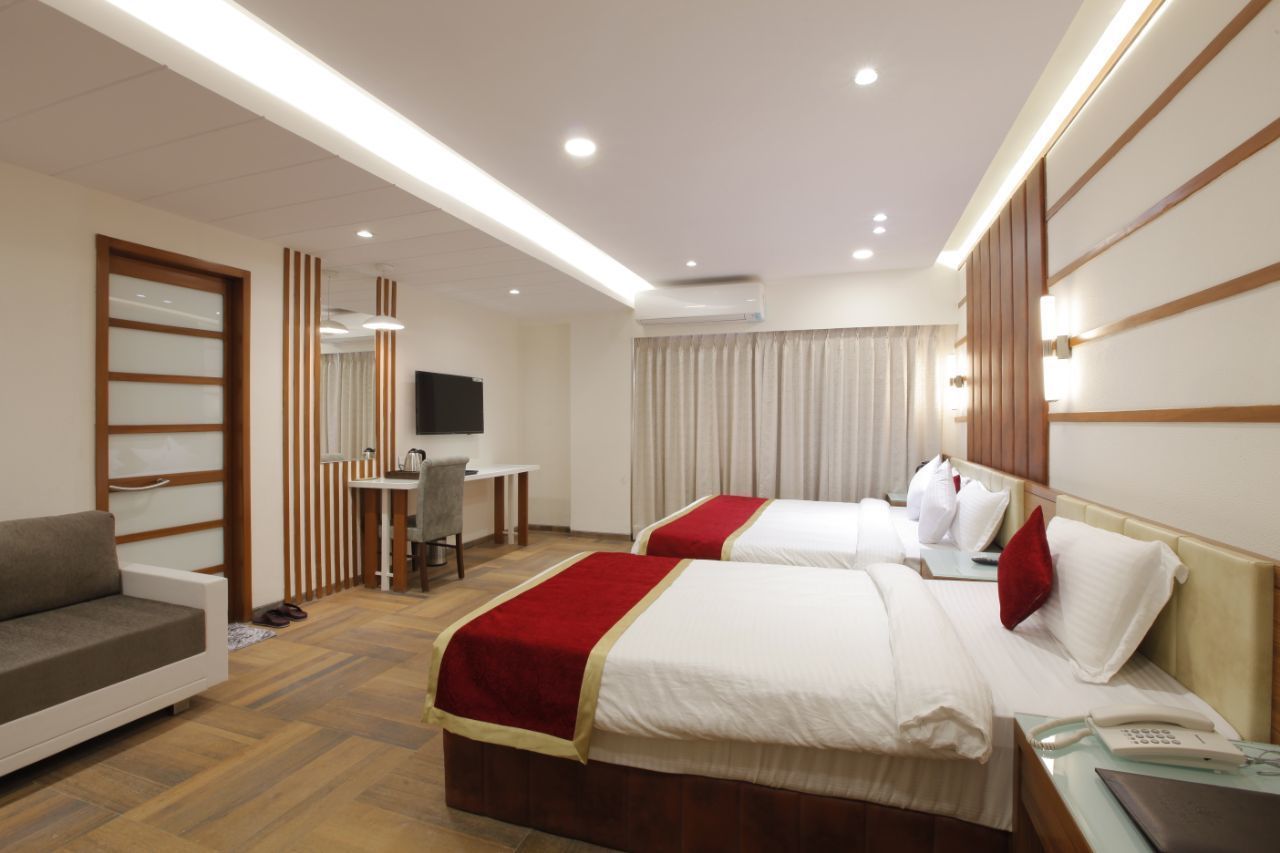 Habitación de hotel con dos camas, un escritorio, un sofá y un televisor.