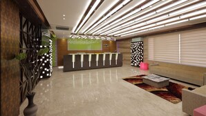 Un moderno área de recepción con una mesa de recepción, una pantalla grande y una zona de estar con un sofá y una mesita de centro.