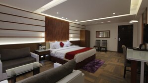 Una habitación de hotel moderna con una cama grande, un sofá, un escritorio y un comedor.