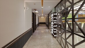Un pasillo de hotel moderno con un separador de vidrio, iluminación empotrada y piso pulido.