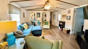 A living room with a sofa, armchair, and a television. -  Ocean Lakes. Pet friendly One Story  with ramp. Complimentary golf cart. (Myrtle Beach)