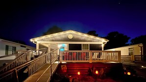 A two-story building with a covered deck and a staircase leading to the entrance. -  Ocean Lakes. Pet friendly One Story  with ramp. Complimentary golf cart. (Myrtle Beach)