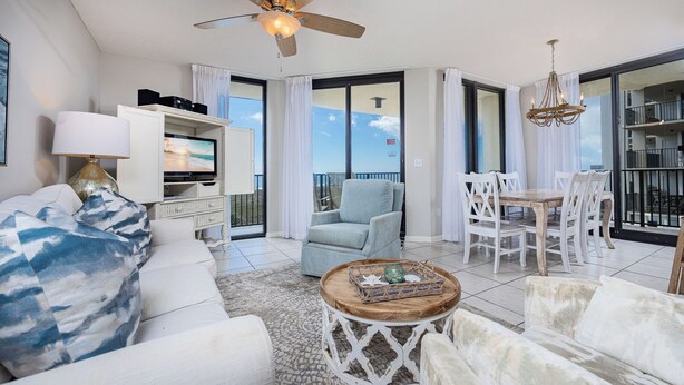 A spacious living room with a white sofa, a coffee table, and a balcony with a view. - Phoenix VIII - 3rd Floor - 3BR (Orange Beach)