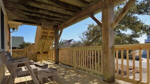 Eine Holzterrasse mit Geländer, einer Bank und einem überdachten Bereich mit geneigtem Dach.