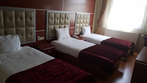 A hotel room with three single beds, a bedside table with a phone, and a window with curtains. - Kafkas Ari Hotel (Ardahan)
