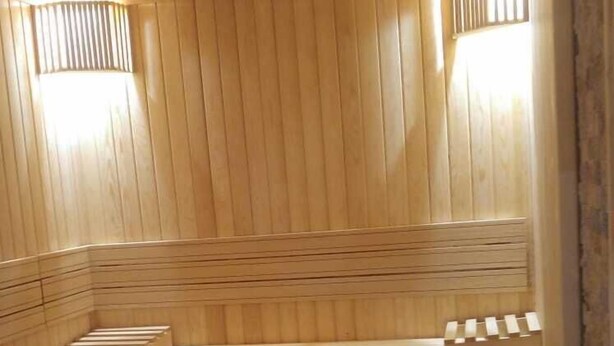 A sauna with wooden benches and a stone heating element. - Kafkas Ari Hotel (Ardahan)