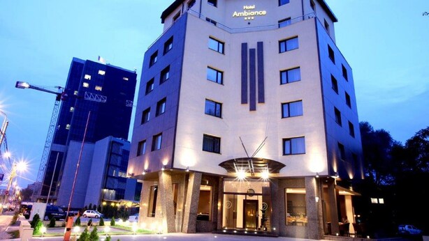 A multi-story hotel with a modern design, featuring a prominent entrance with a glass facade and illuminated signage.