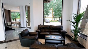 A modern lobby with leather sofas, a coffee table, and a potted plant.