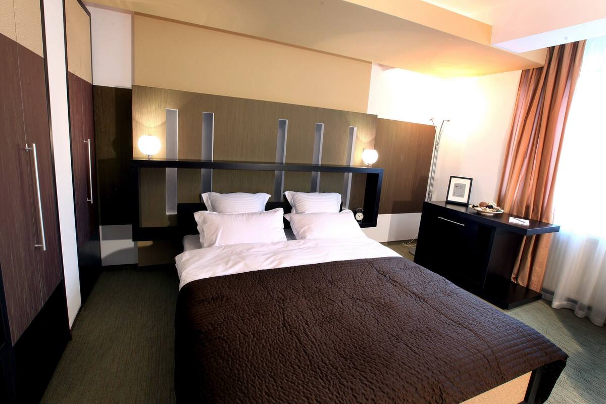A hotel room with a large bed, a desk, and a wardrobe.