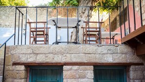 A stone building with a balcony featuring a table and chairs. - Rodi Hotel - Adults Only (Rhodes)