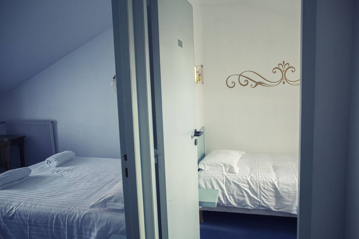 A bedroom with a single bed, a radiator, and a door leading to another room.