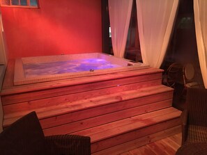 A hot tub with a tiled interior, wooden steps, and wicker chairs. - The Old Hotel Ravel (Clermont-Ferrand)