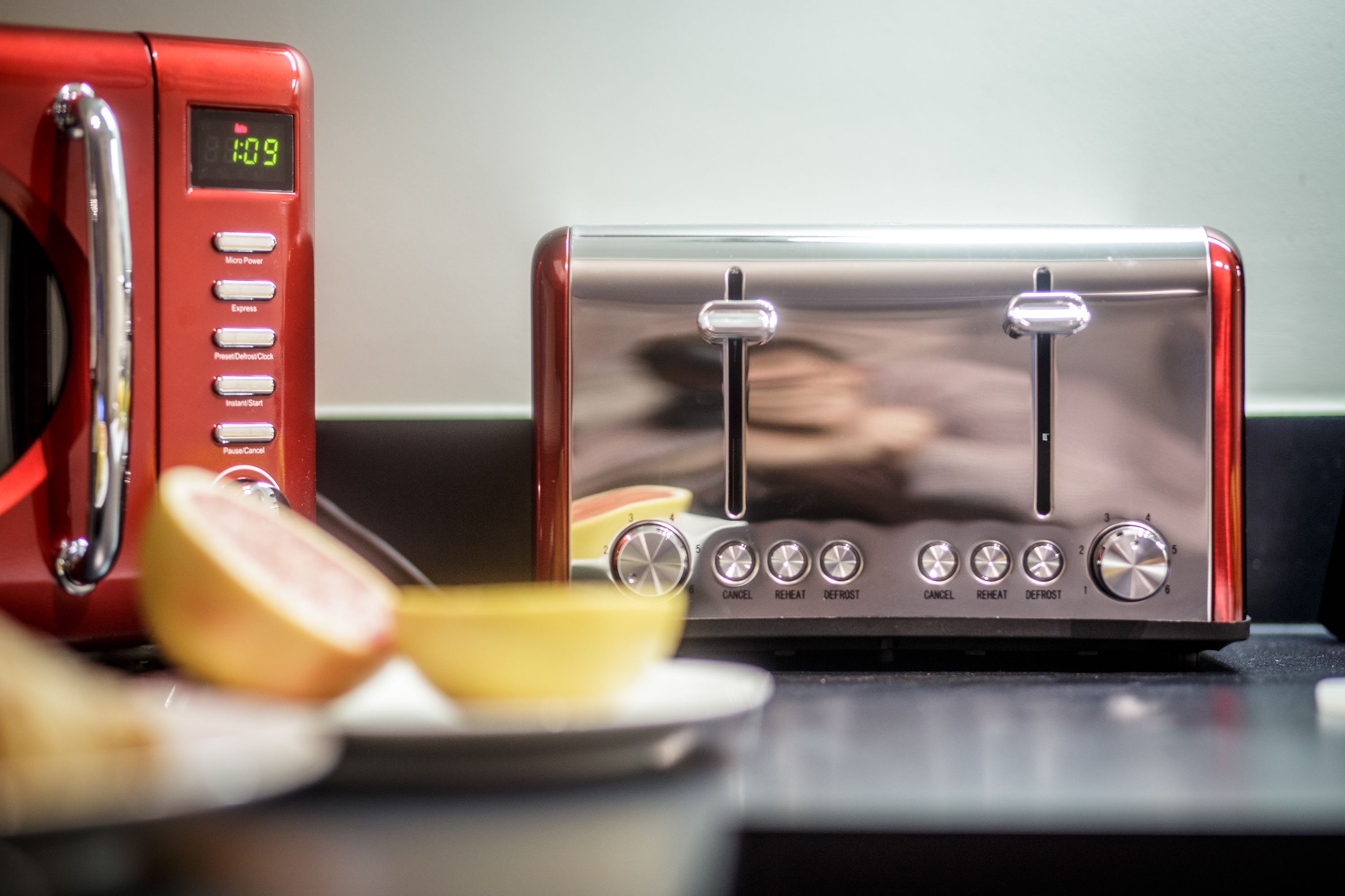 A red and a silver toaster on a kitchen counter with a digital clock displaying 8:09.