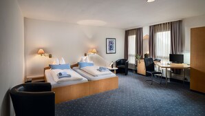 A hotel room with a bed, a desk, a chair, and a television. - Sunibel Inn Hotel (Reinheim)