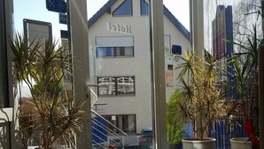 A hotel entrance with a glass door, potted plants, and a tiled floor. - Sunibel Inn Hotel (Reinheim)