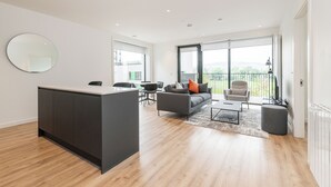 A modern living room with a sofa, coffee table, and a dining area with chairs. - The Grange Dublin (Dublin)