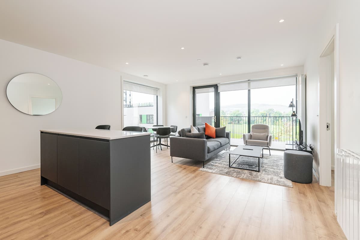 A modern living room with a sofa, coffee table, and a dining area with chairs.