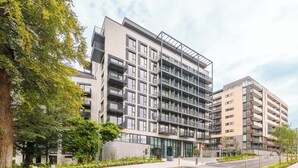 A multi-story residential building with balconies, a glass entrance, and a landscaped area with trees and plants. - The Grange Dublin (Dublin)