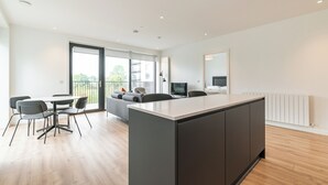 A modern kitchen with a central island, dining area with chairs, and a sofa. - The Grange Dublin (Dublin)