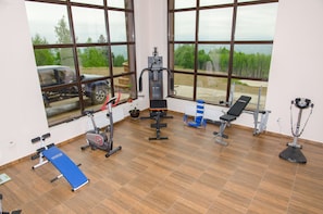 A gym with exercise equipment, large windows, and a view of the outdoors. - Poiana Viselor (Poiana Marului)