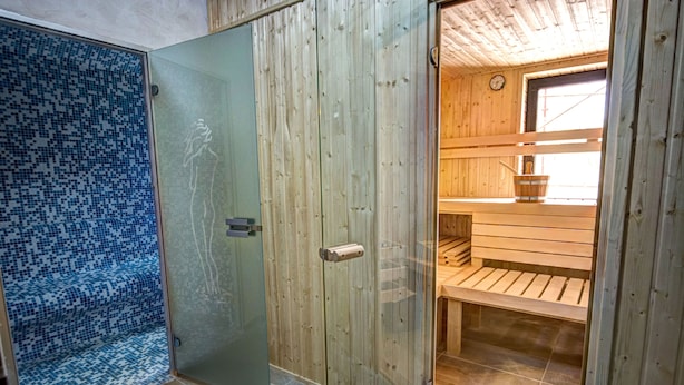 Un interior de madera con cabina de ducha de vidrio y un banco de madera.