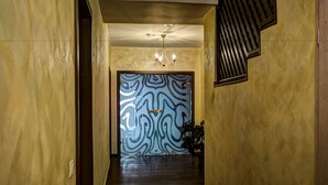 Un pasillo con un papel tapiz decorativo, una araña de cristal y una planta.