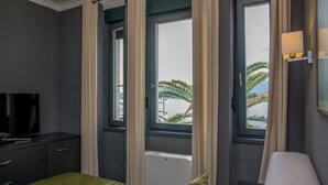Habitación de hotel con cama, televisor y ventana con cortinas.