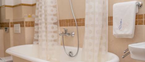 A bathroom with a freestanding bathtub, a shower, a sink, and a towel rack.