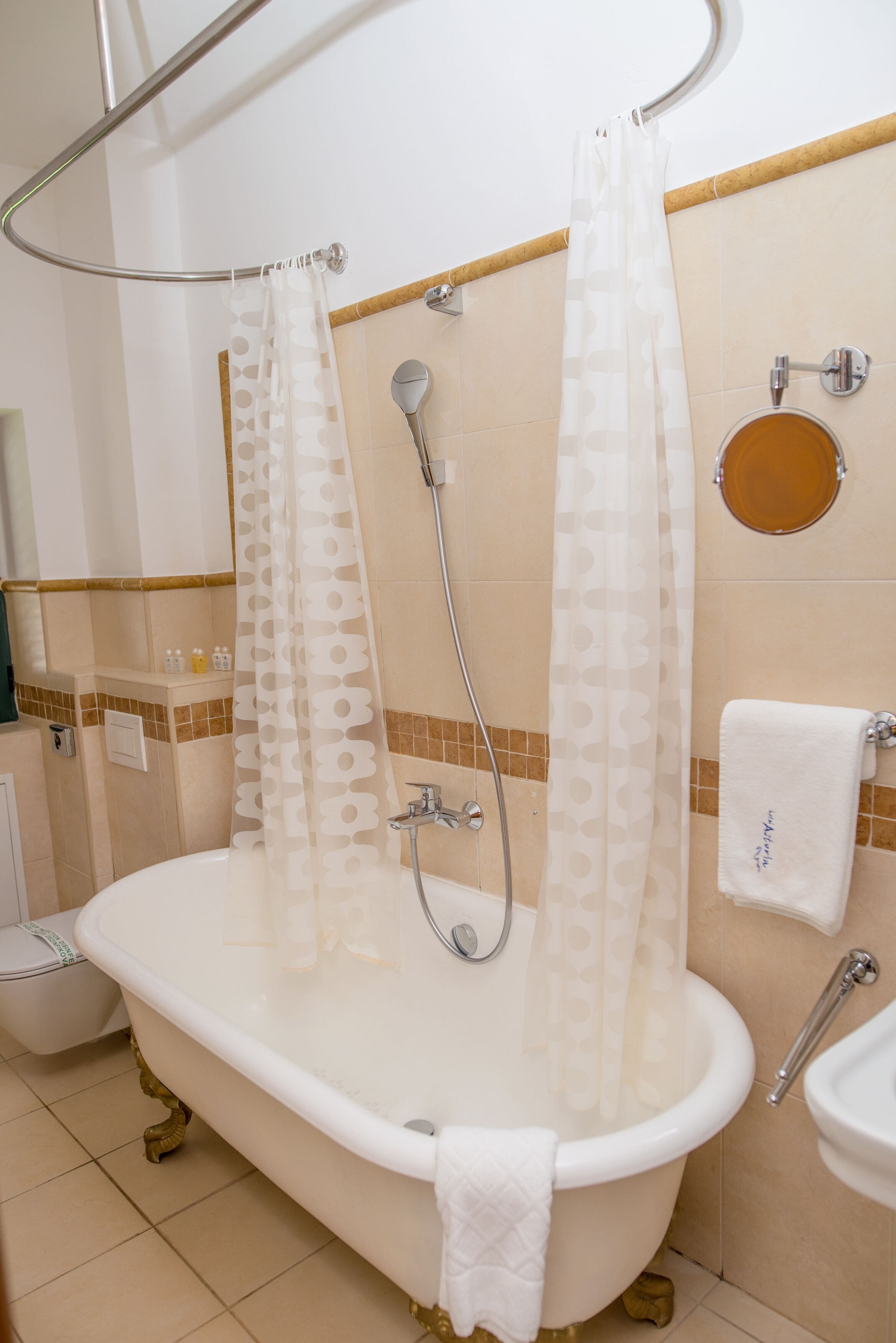 A bathroom with a freestanding bathtub, a shower curtain, a towel rack, and a sink.