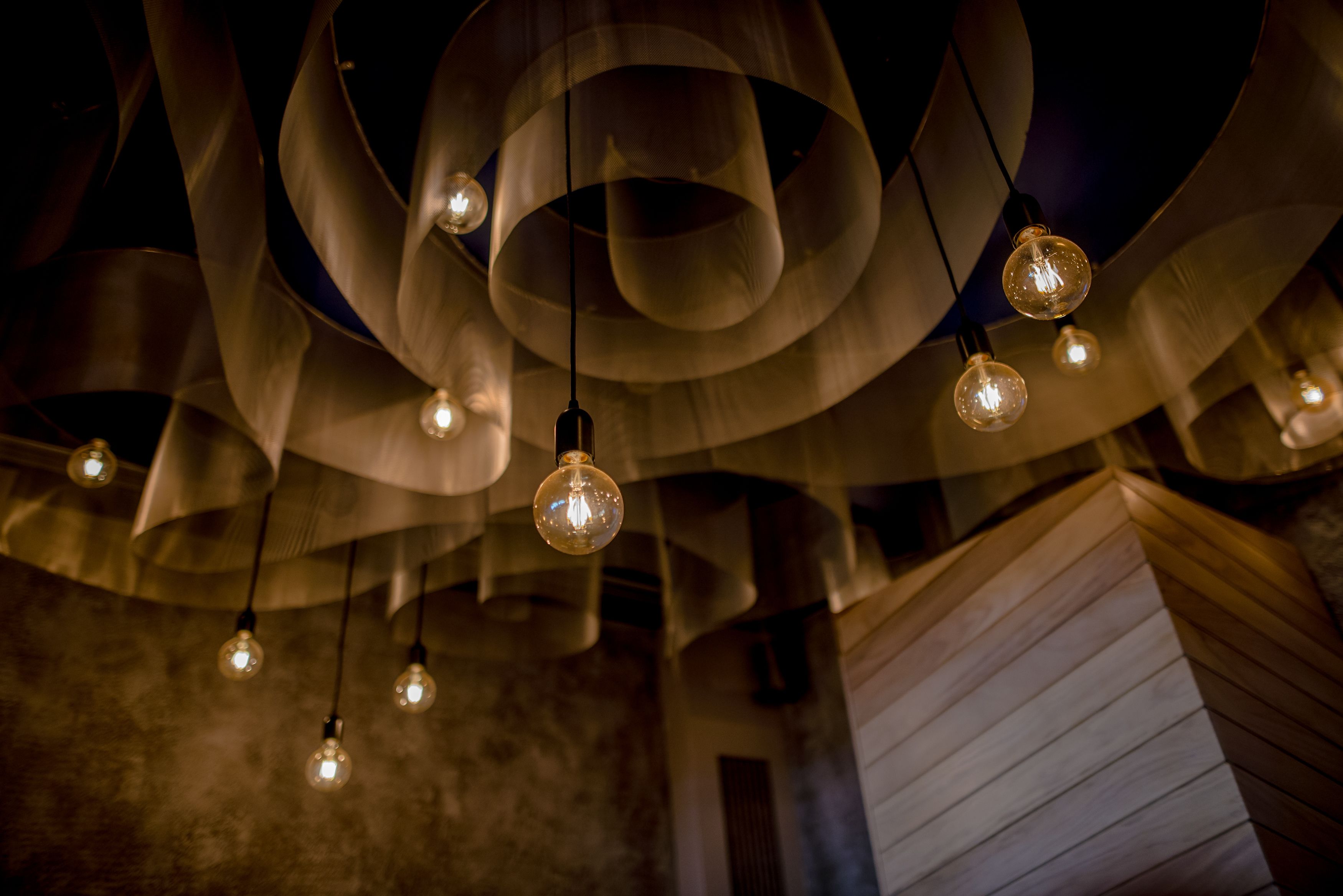 Un plafond orné de nombreuses lampes suspendues et un mur recouvert de lambris en bois.