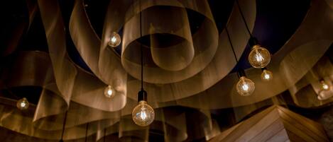 Un plafond orné de nombreuses lampes suspendues et un mur recouvert de lambris en bois.